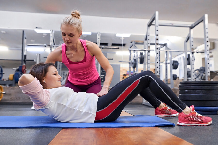 A FitnessWorks coach guiding a client through a core exercise